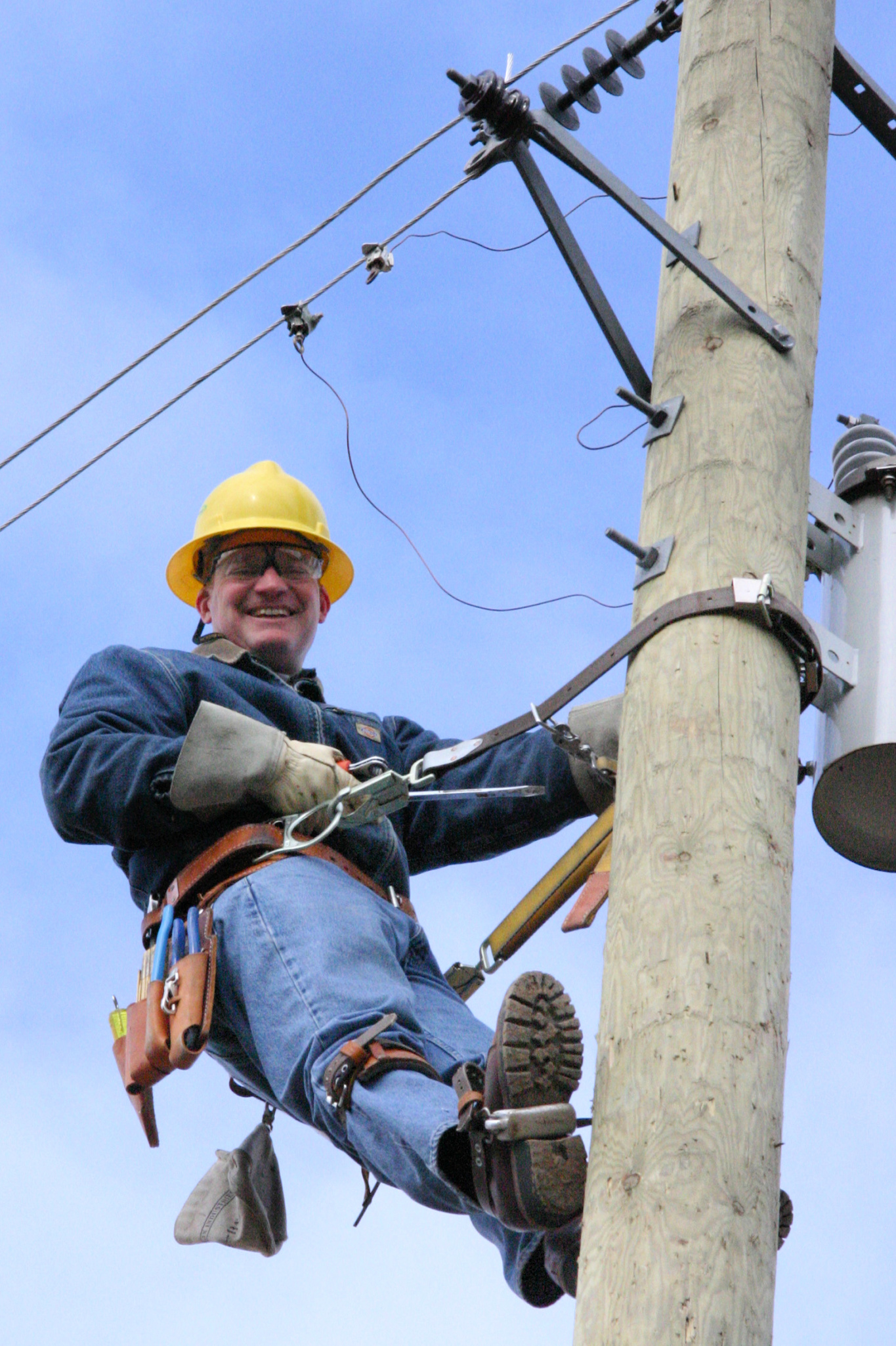 Roy Smith smiles at the camera while climbing a pole