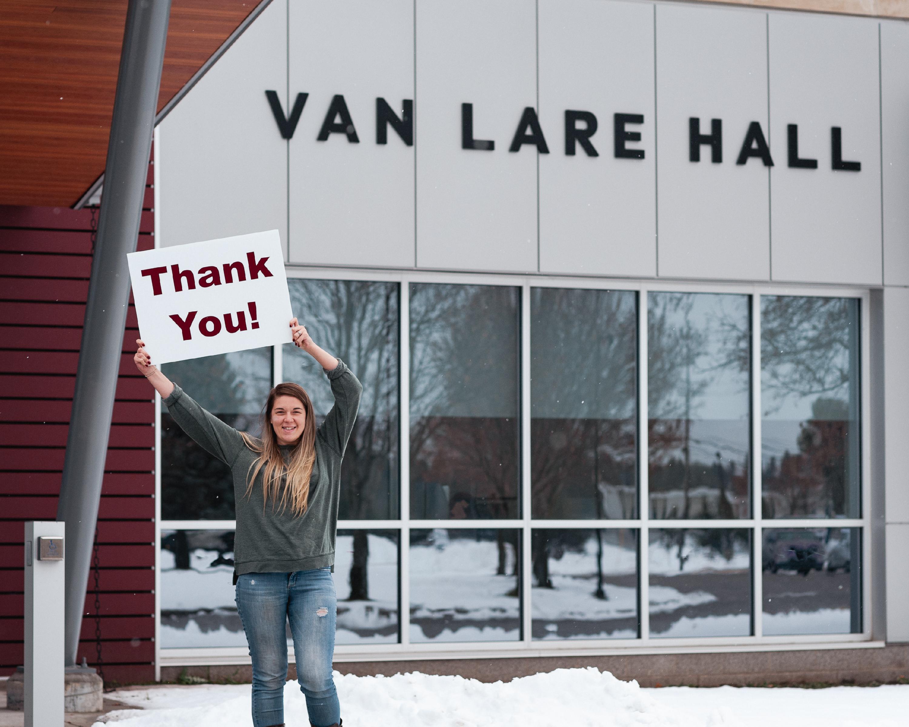 Student in front of Van Lare Hall holding a thank you sign