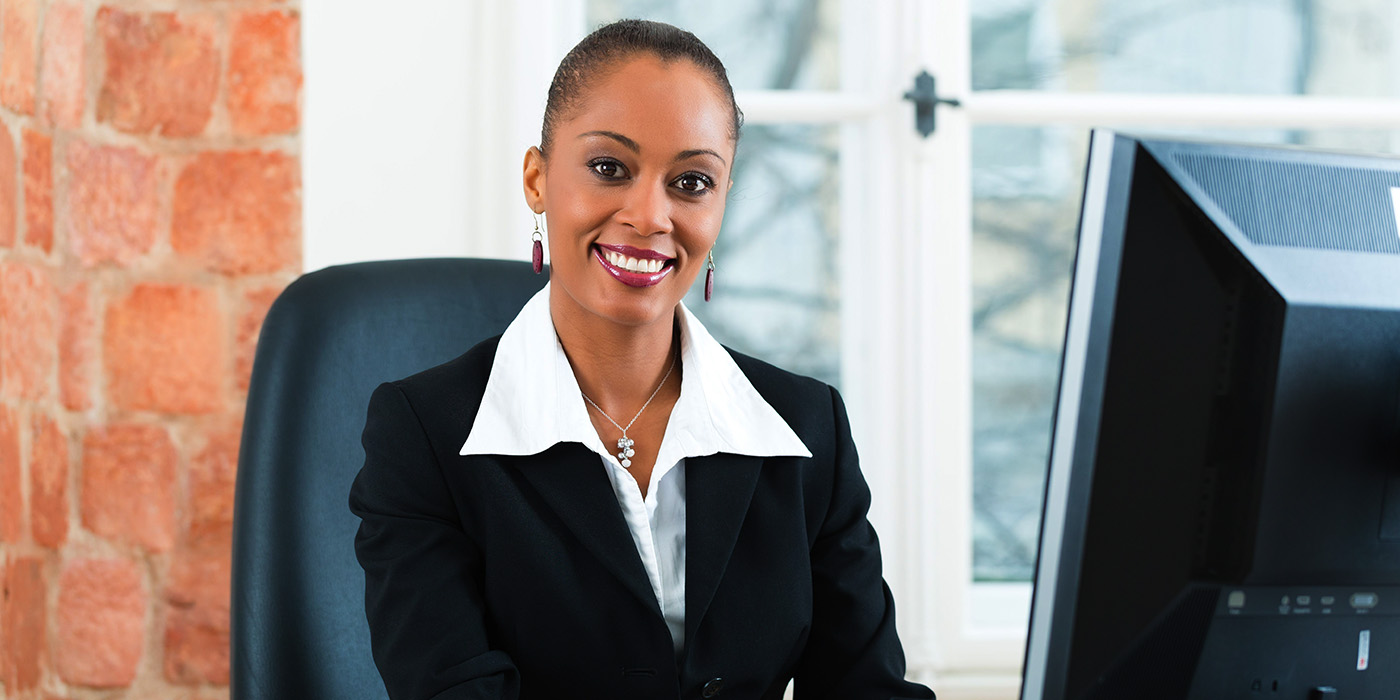 A paralegal smiles while sitting at a computer