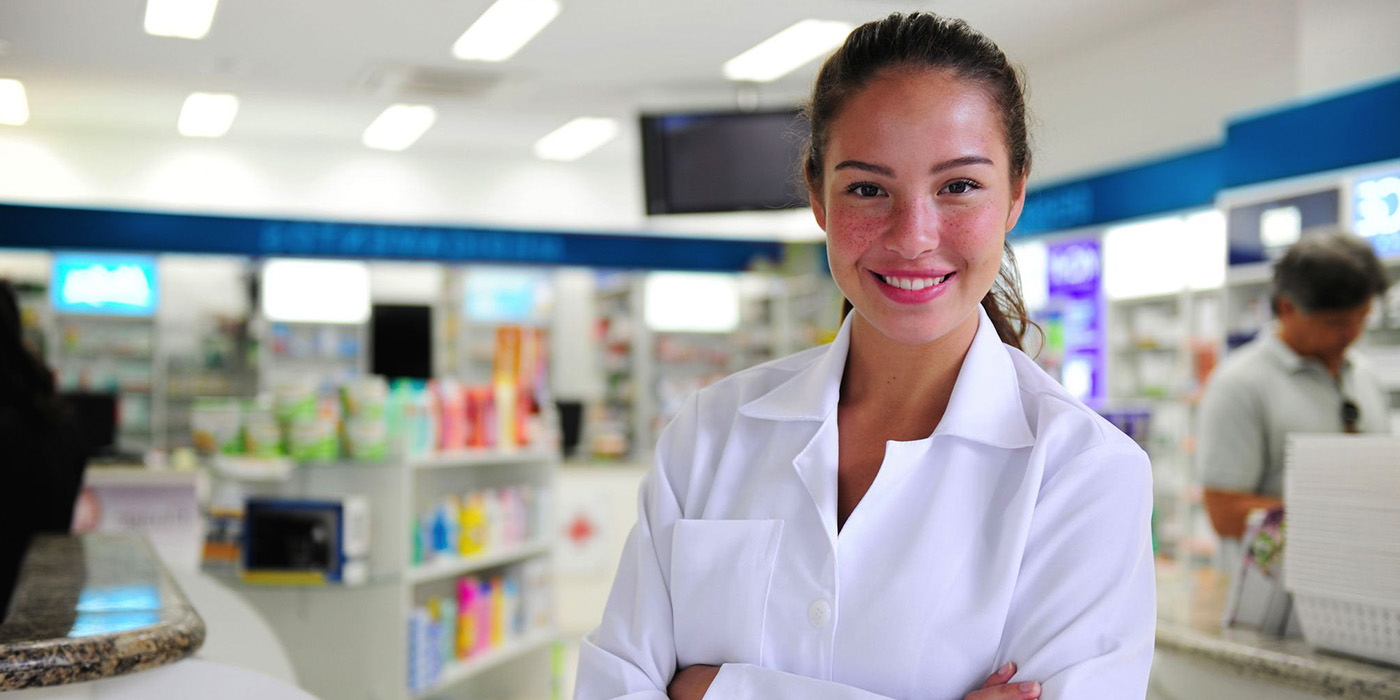 A pharmacy technician stands in the front of a pharmacy