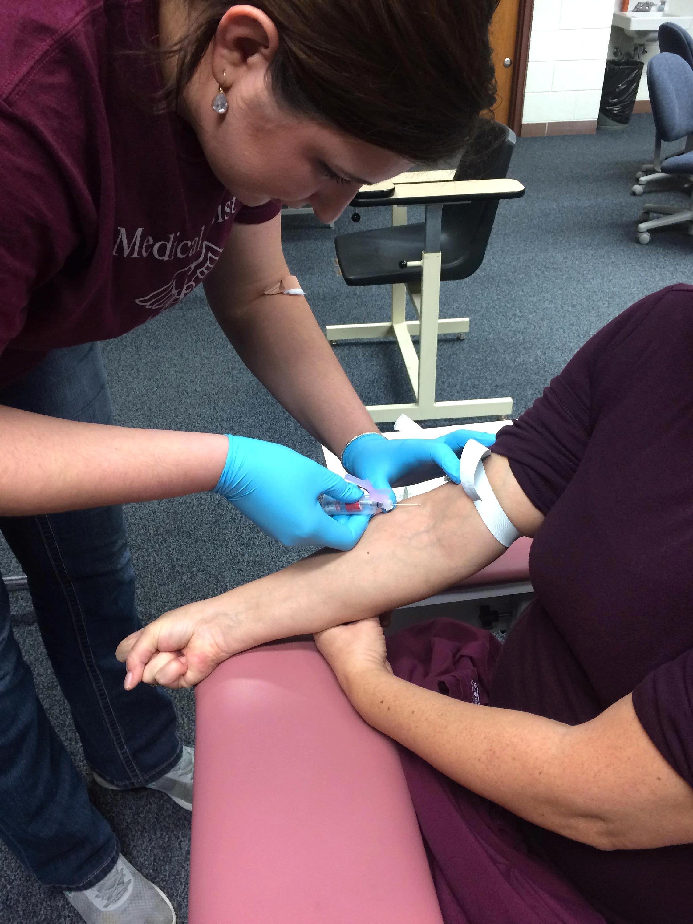 Medical Assistant student inserting needle in another student's vein