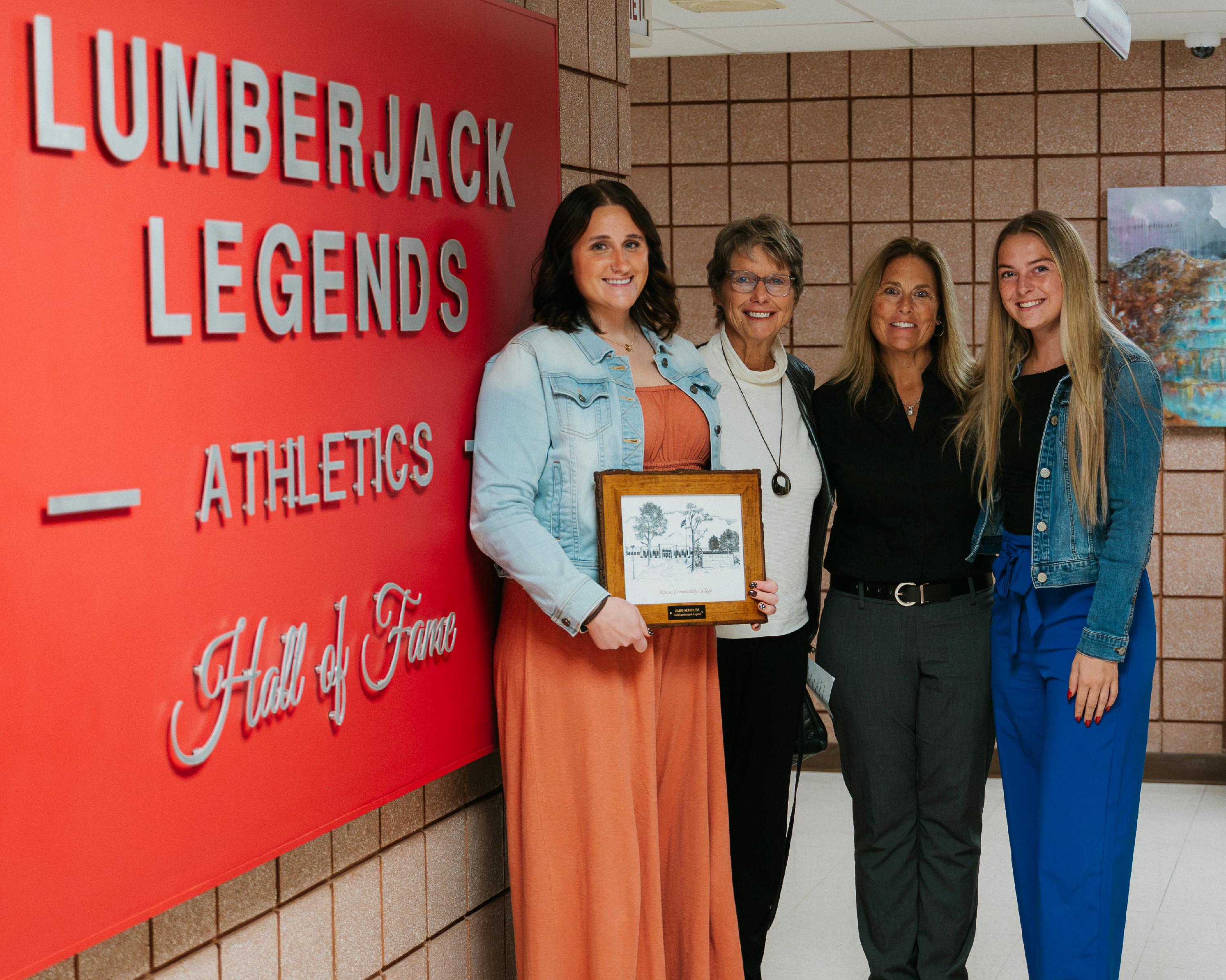Jade Schultz, Cindy DeRocher and friends in front of Lumberjack Legends sign