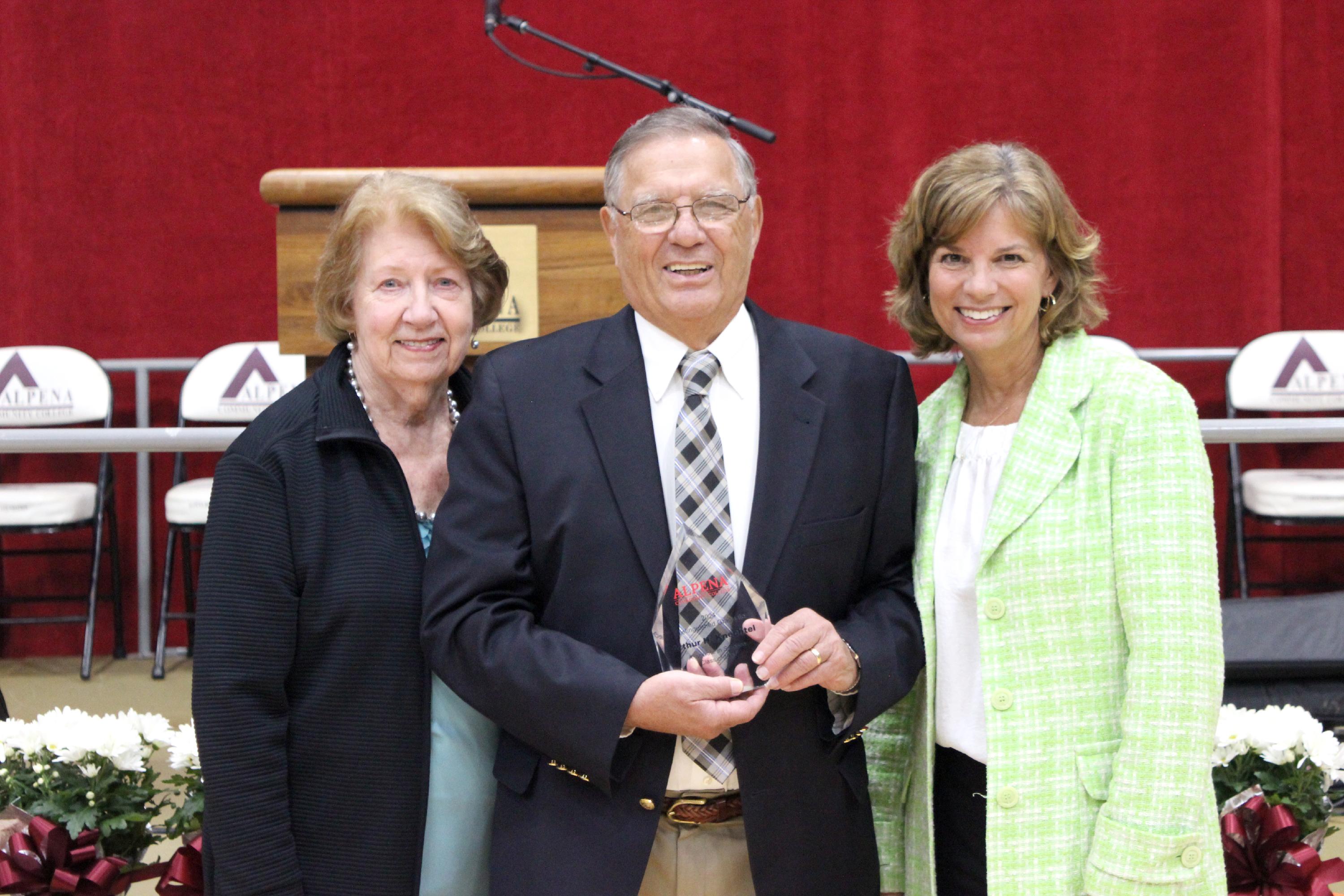 Art Knechtel poses with his award alongside his wife and daughter