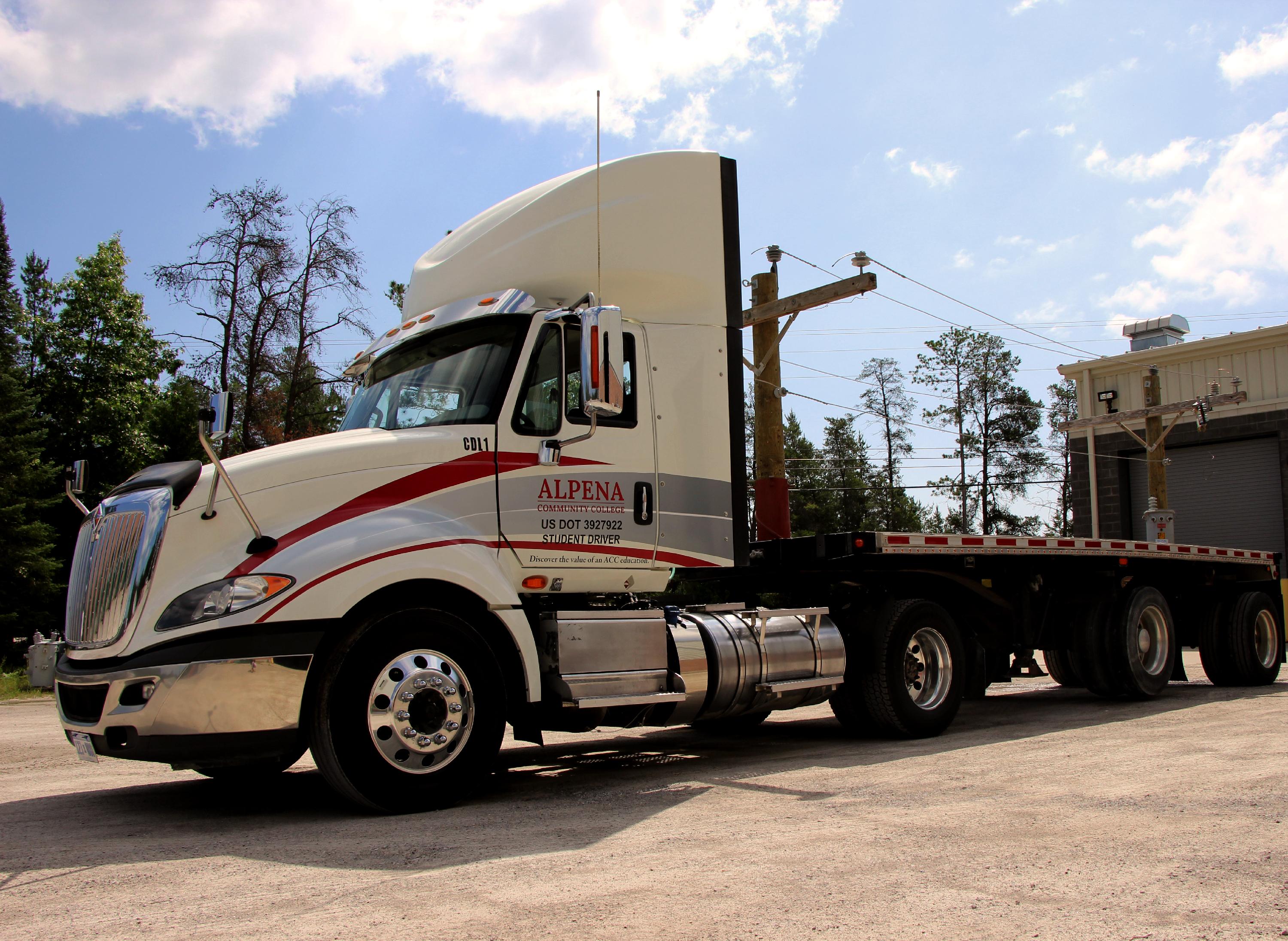 A semi truck with ACC's logo on it is parked in a lot on a sunny day