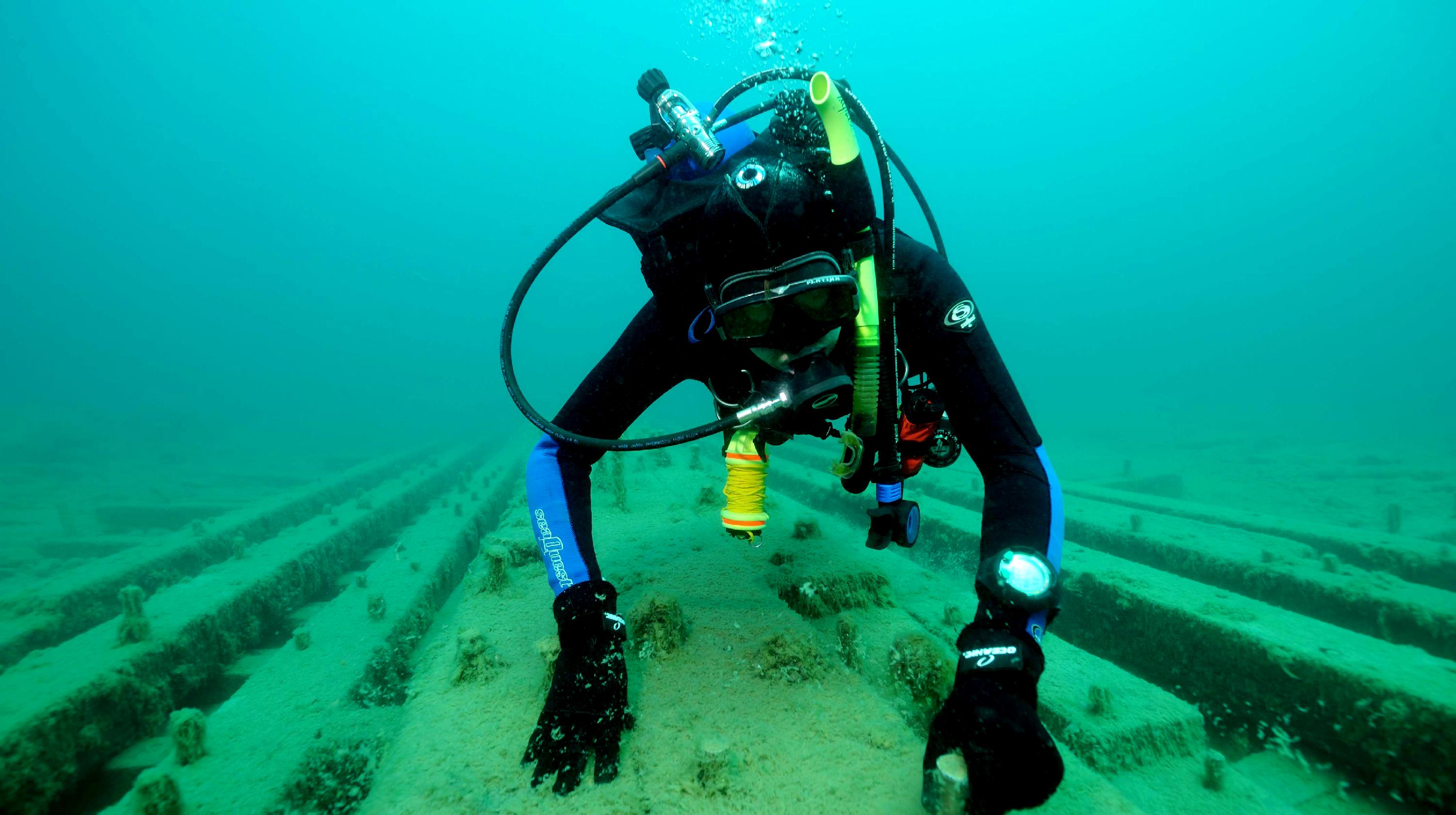 A scuba diver examines an abandoned shipwreck under water