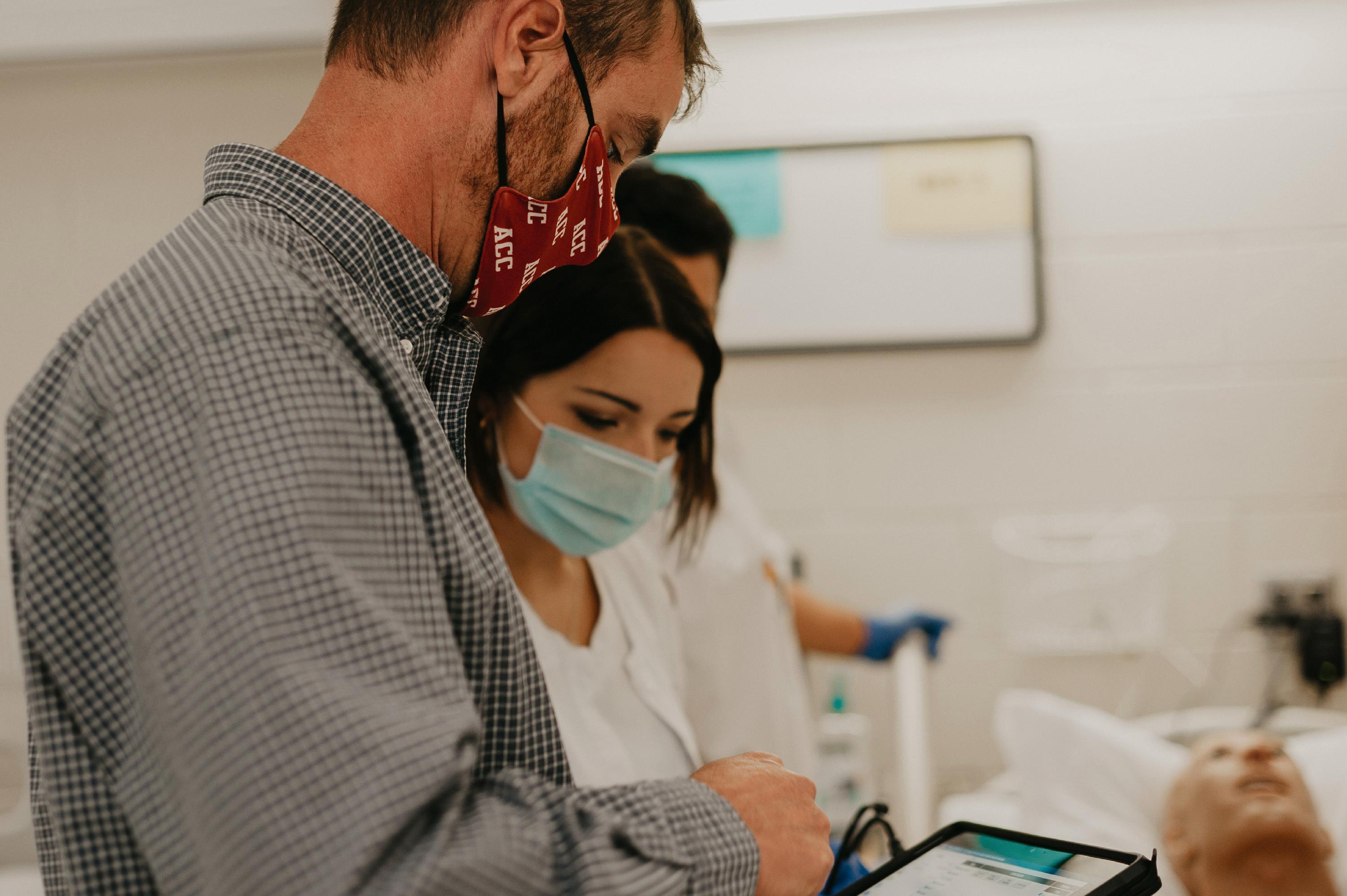 A staff member and a student look at data on a tablet