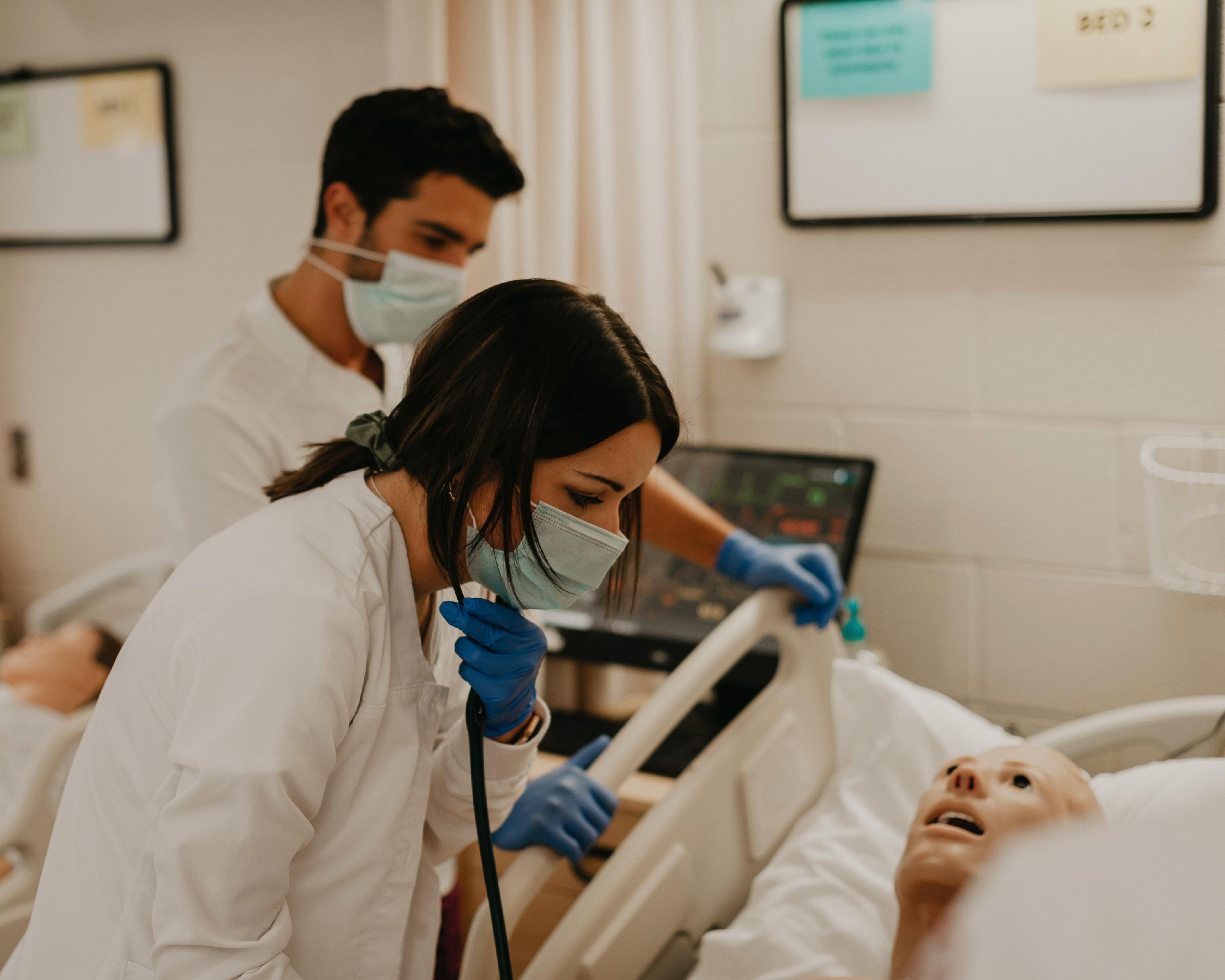 A male and a female nursing student work on a manikin